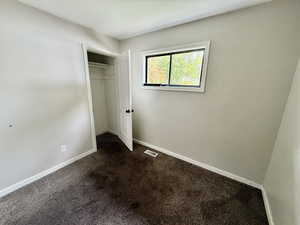 Unfurnished bedroom with dark carpet and a closet