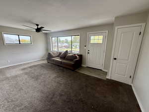 Carpeted living room with healthy amount of natural light and ceiling fan