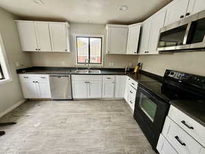 Kitchen featuring appliances with stainless steel finishes, white cabinetry, dark countertops, and recessed lighting