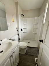 Bathroom featuring dark wood-style floors, vanity, and a shower stall