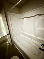Full bathroom featuring dark wood-type flooring and tub / shower combination