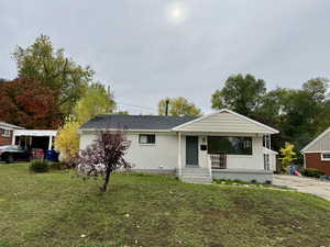 View of front of property with covered porch, a front yard, and brick siding