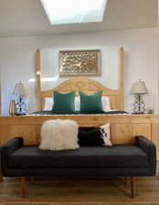Bedroom with a textured wall, wood finished floors, and a skylight