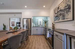 Kitchen featuring gray cabinets, stainless steel appliances, light wood-style floors, and recessed lighting