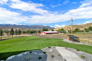 View of home's community with an outdoor structure, a pole building, a mountain view, and a view of countryside