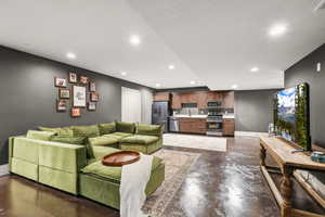 Living room with finished concrete floors, a textured ceiling, and recessed lighting