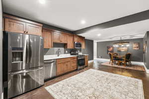 Kitchen with appliances with stainless steel finishes, concrete floors, brown cabinetry, recessed lighting, and pendant lighting