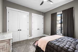 Carpeted bedroom with multiple closets and ceiling fan