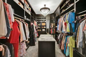 Walk in closet with light carpet and a chandelier