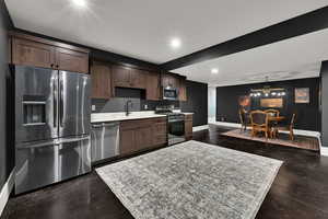 Kitchen featuring appliances with stainless steel finishes, a chandelier, dark brown cabinetry, recessed lighting, and hanging light fixtures