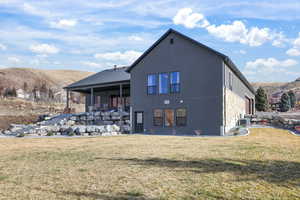 Rear view of house featuring a mountain view, a patio, a lawn, and stucco siding