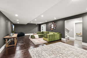 Living room with finished concrete flooring, recessed lighting, and stairs