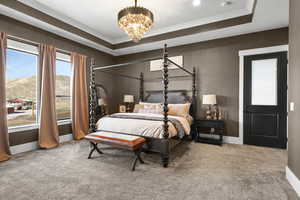 Carpeted bedroom featuring a mountain view, a chandelier, crown molding, and a tray ceiling