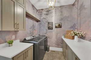 Laundry room featuring separate washer and dryer, a chandelier, wallpapered walls, cabinet space, and light tile patterned flooring