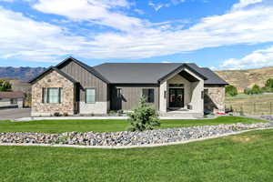 View of front facade with board and batten siding, a mountain view, covered porch, and a front lawn