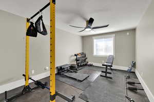 Workout area featuring a textured ceiling, a ceiling fan, and dark flooring