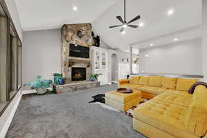 Carpeted living room with high vaulted ceiling, a fireplace, built in features, arched walkways, and a ceiling fan