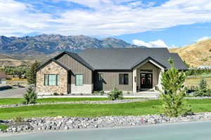 View of front facade featuring board and batten siding, a mountain view, a porch, a front yard, and stone siding