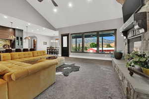 Carpeted living room featuring high vaulted ceiling, arched walkways, recessed lighting, a ceiling fan, and a chandelier