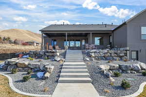 Rear view of property featuring a ceiling fan, a patio, stucco siding, and a mountain view