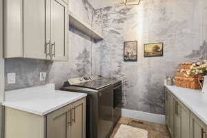 Laundry room with washer and clothes dryer, light stone finish floors, and cabinet space