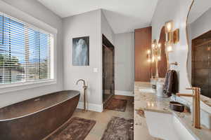 Mater bathroom featuring a shower stall, a soaking tub, double vanity, and light tile patterned floors