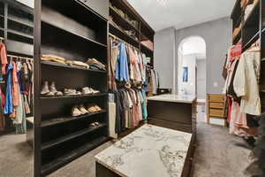Walk in closet with dark colored carpet and arched walkways