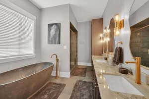 Full bath featuring a shower stall, a freestanding tub, and double vanity