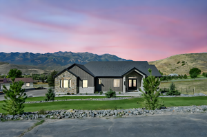 View of front facade with a mountain view, board and batten siding, stone siding, and a front lawn