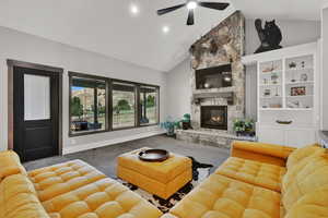 Living room with high vaulted ceiling, carpet flooring, a stone fireplace, a ceiling fan, and recessed lighting
