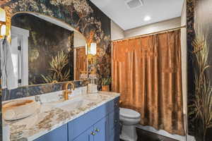 Full bath featuring wallpapered walls and vanity