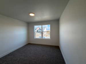 Carpeted empty room with a textured ceiling and baseboards