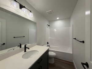 Bathroom featuring vanity, bathtub / shower combination, and dark wood-type flooring