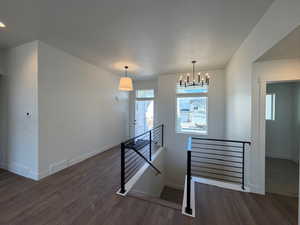 Staircase with wood finished floors and a chandelier