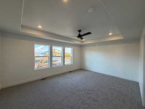 Carpeted spare room featuring a tray ceiling, a ceiling fan, a smoke detector, and recessed lighting