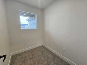 Unfurnished room featuring dark colored carpet and baseboards