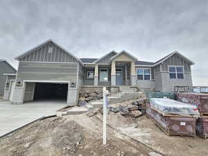 View of front facade with board and batten siding, a garage, concrete driveway, and covered porch