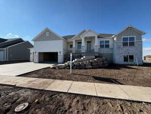 Craftsman inspired home with board and batten siding, a porch, stone siding, and a garage
