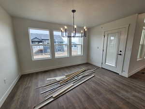 Unfurnished dining area with a chandelier and dark wood finished floors