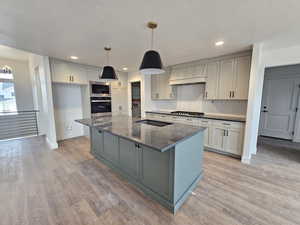 Kitchen featuring gray cabinets, decorative backsplash, appliances with stainless steel finishes, a large island, and pendant lighting
