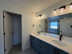 Full bath featuring double vanity, light tile patterned flooring, and a bath