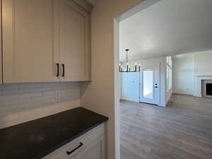 Kitchen with a textured ceiling, a chandelier, backsplash, dark wood-style floors, and decorative light fixtures