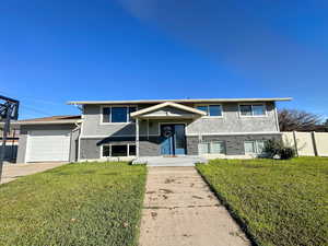 View of front of house featuring brick siding, stucco siding, an attached garage, and driveway