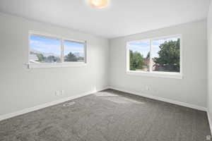 Carpeted spare room featuring baseboards