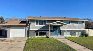 Split foyer home featuring brick siding, stucco siding, an attached garage, a mountain view, and driveway