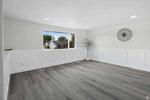 Unfurnished dining area with a decorative wall, wainscoting, light wood-style flooring, and recessed lighting