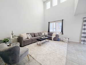 Living room with light tile patterned floors, plenty of natural light, and a high ceiling