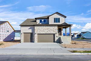 View of front of house with covered porch, stone siding, driveway, board and batten siding, and a residential view
