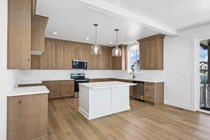 Kitchen with decorative light fixtures, stainless steel appliances, brown cabinetry, beamed ceiling, and recessed lighting