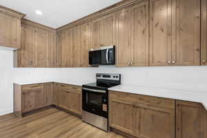 Kitchen featuring stainless steel appliances, brown cabinetry, light wood-style flooring, and recessed lighting
